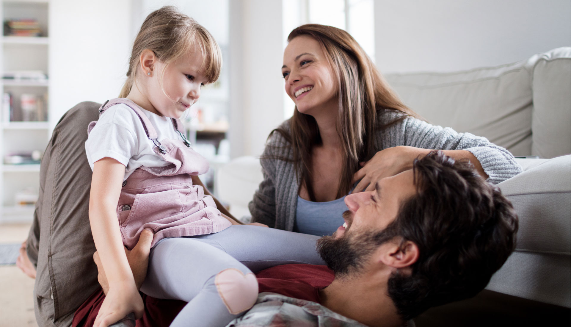 Padre y madre tumbados jugando con su hija
